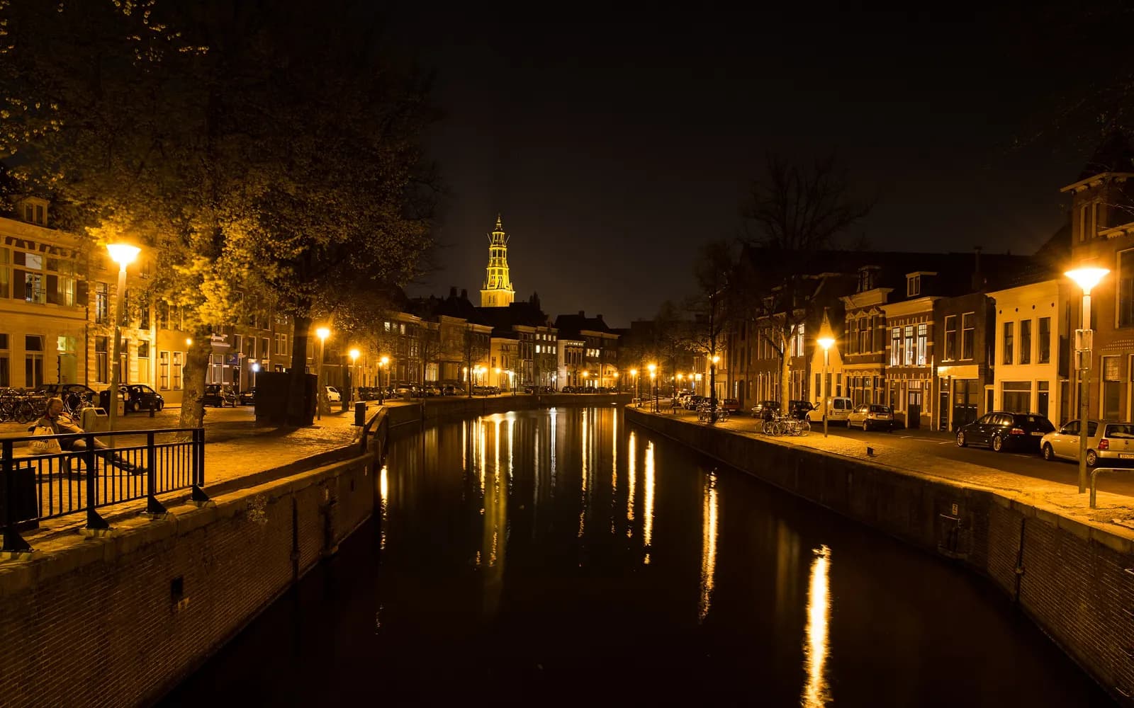 Gracht in Groningen bij avond, met de verlichte Martinitoren in de verte